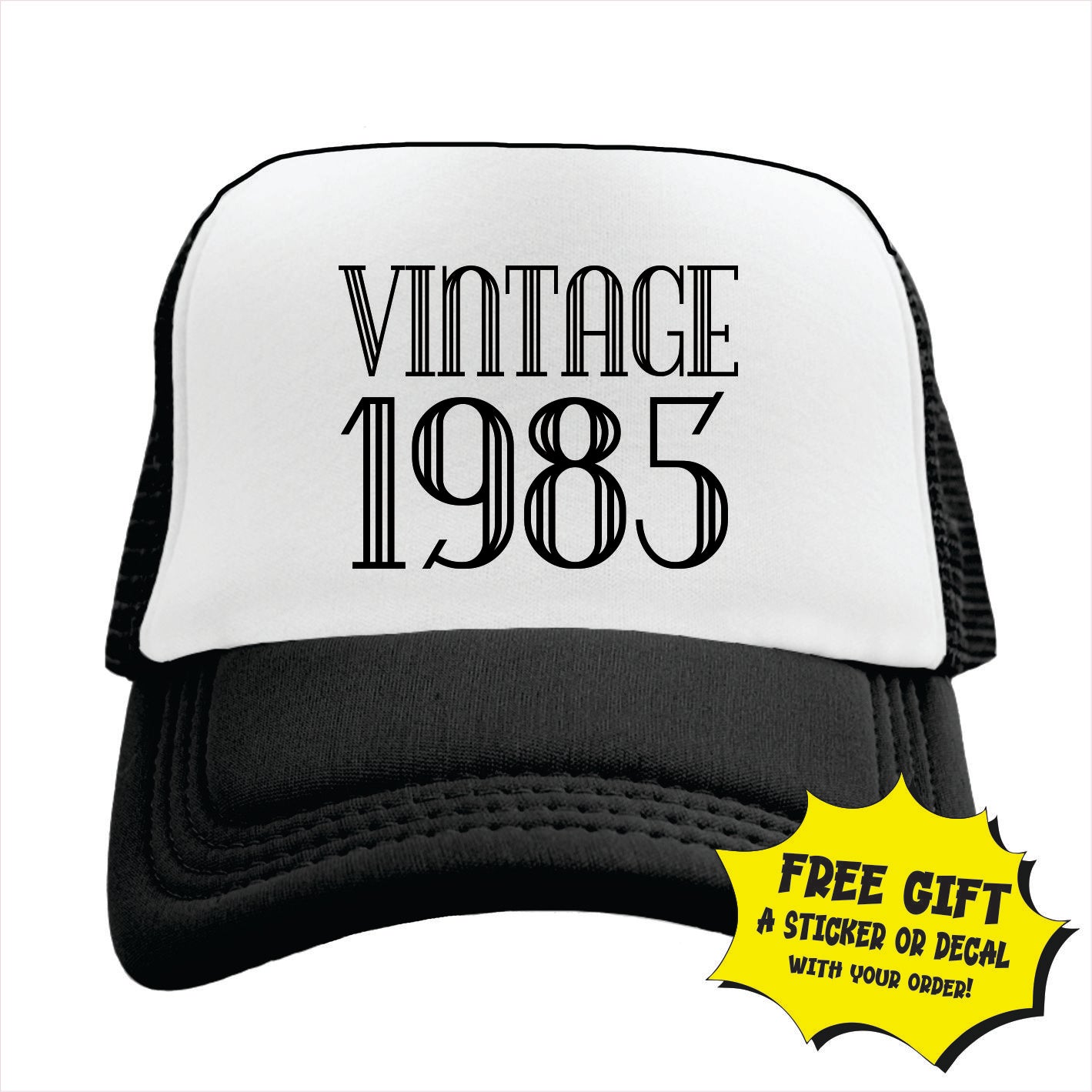 Black and white trucker hat cap with 'VINTAGE 1985' printed in black text on the front panel.