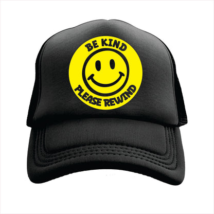 Black trucker hat with a round yellow sticker featuring a smiley face and the text 'BE KIND PLEASE REWIND' on the front.