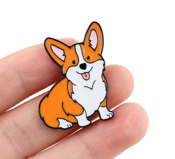 enamel pin in a hand with a corgi dog design from ecorootstore.com