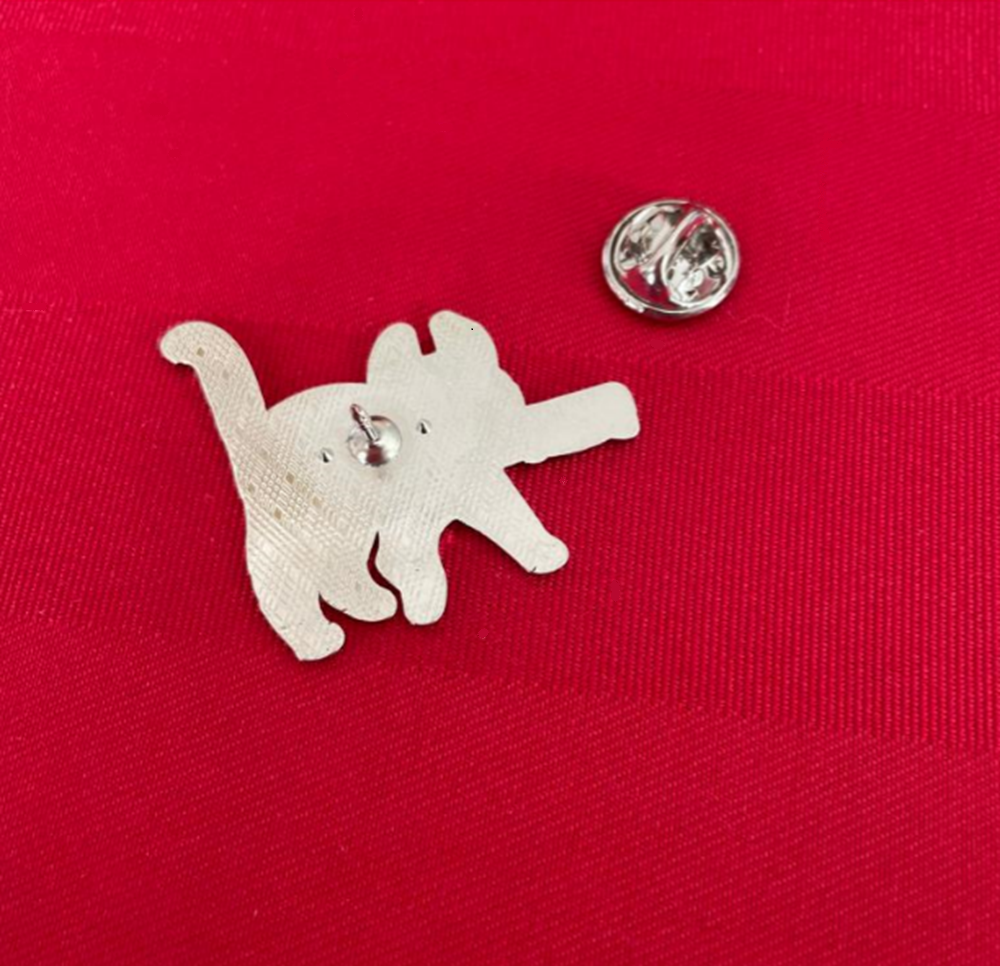 back of enamel pin with a black cat carrying a knife, and a metal clasp