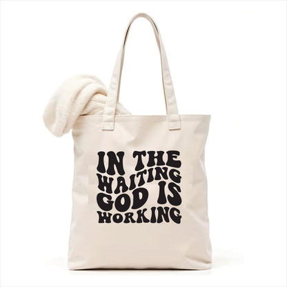 white tote bag with 'In the waiting God is working' text on a white background