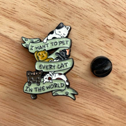 enamel pin with many little cats saying i want to pet every cat in the world, and a rubber clasp