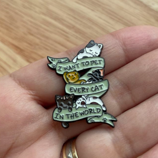 enamel pin with many little cats saying i want to pet every cat in the world