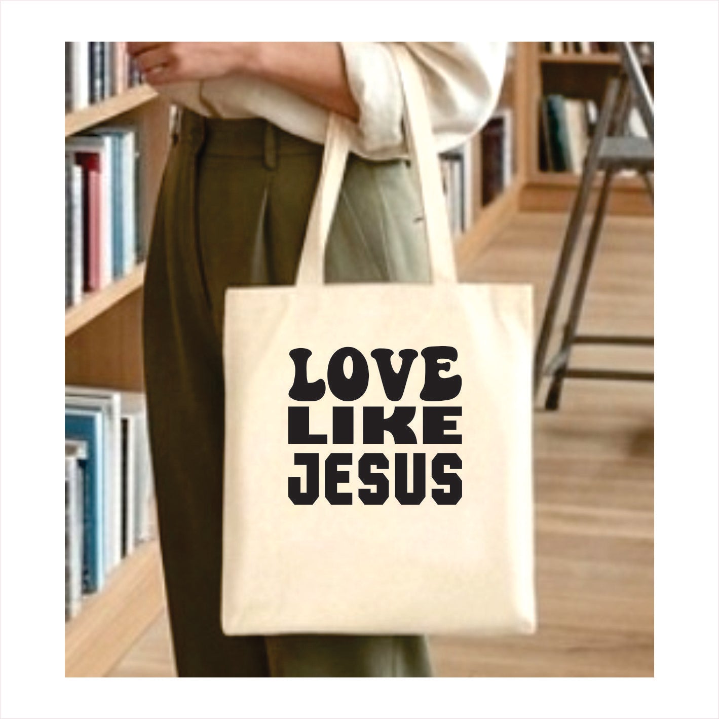 Tote bag with 'Love Like Jesus' text held by a person in a library setting