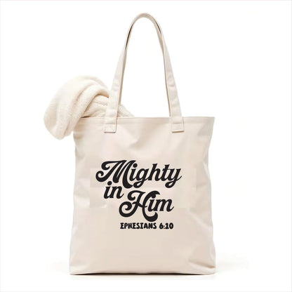 white tote bag with 'Mighty in Him Ephesians 6:10' text on a white background