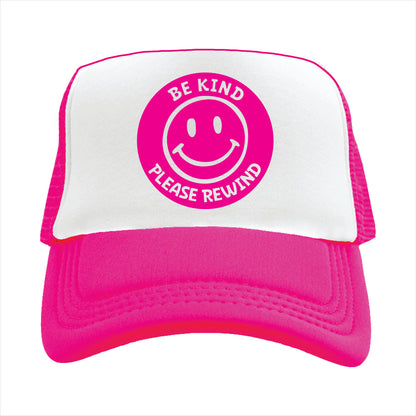 Pink and white trucker hat with a round pink featuring a smiley face and the text 'BE KIND PLEASE REWIND' on the front.