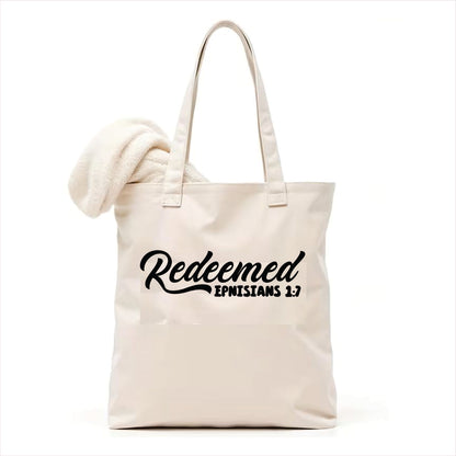 white tote bag with 'Redeemed Ephesians 1:7' text on a white background