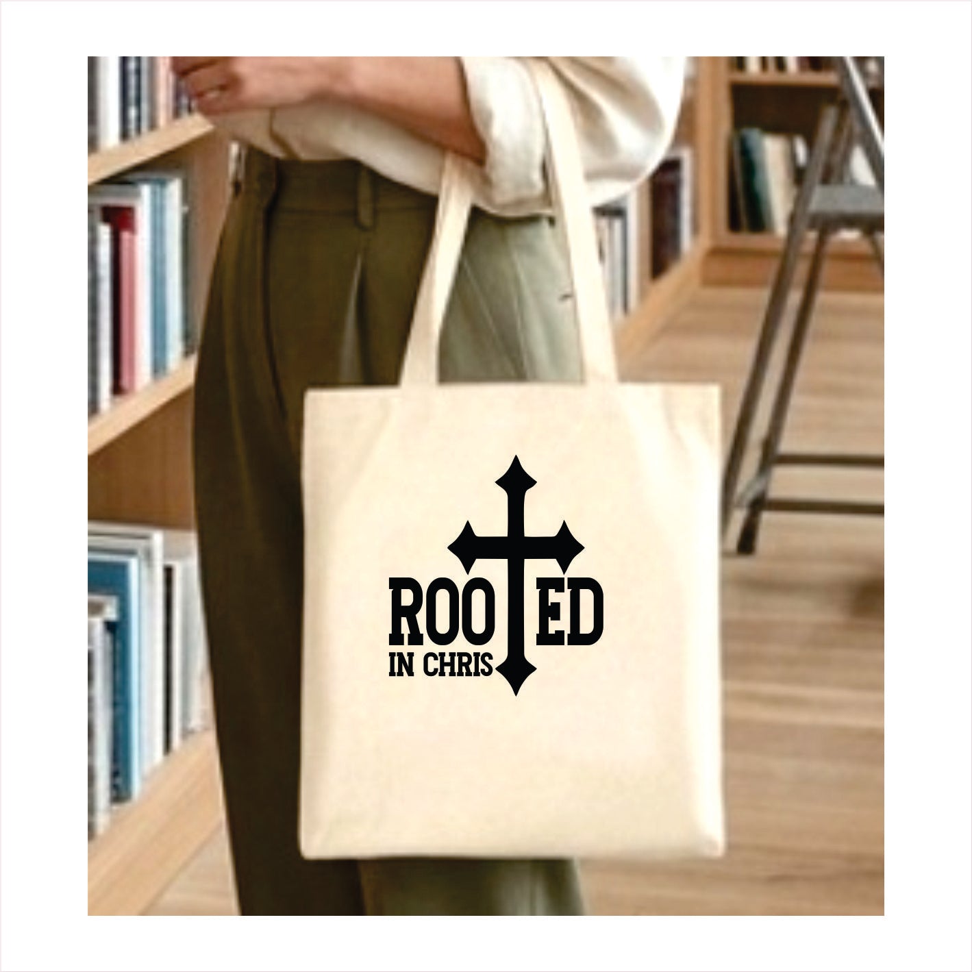 Tote bag with 'Rooted in Chris' design held by a person in a library setting