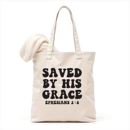 white tote bag with 'Saved by His Grace' text on a white background