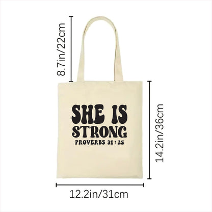 white tote bag with 'SHE IS STRONG' text and measurements on a white background