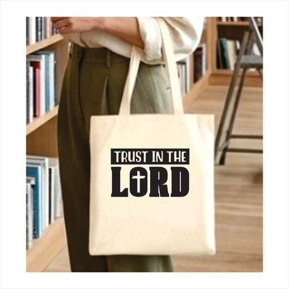 Person holding a tote bag with 'Trust in the Lord' text in a library setting