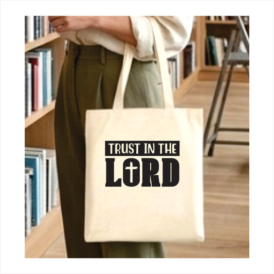 Person holding a tote bag with 'Trust in the Lord' text in a library setting