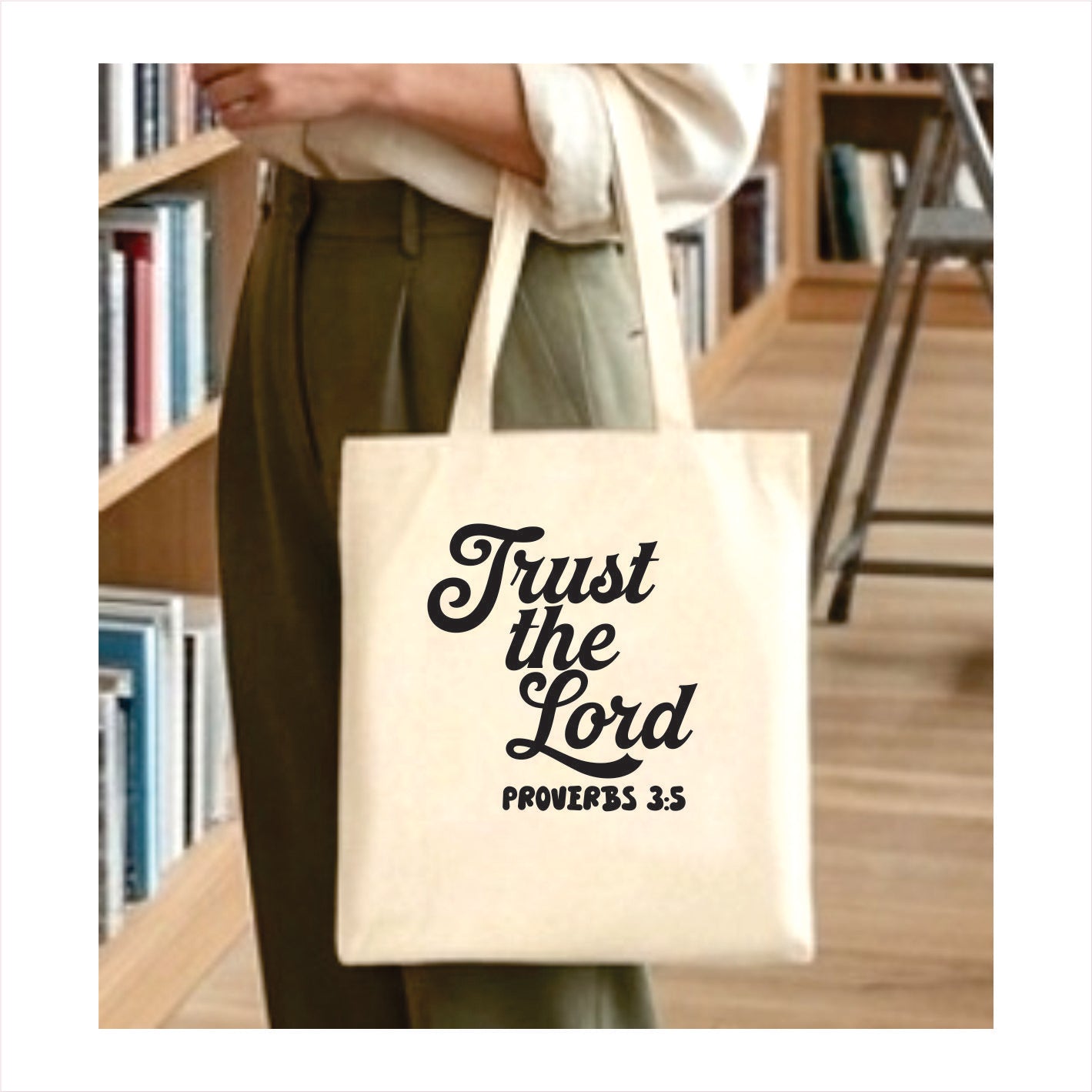 Tote bag with 'Trust the Lord Proverbs 3:5' text held by a person in a library setting.