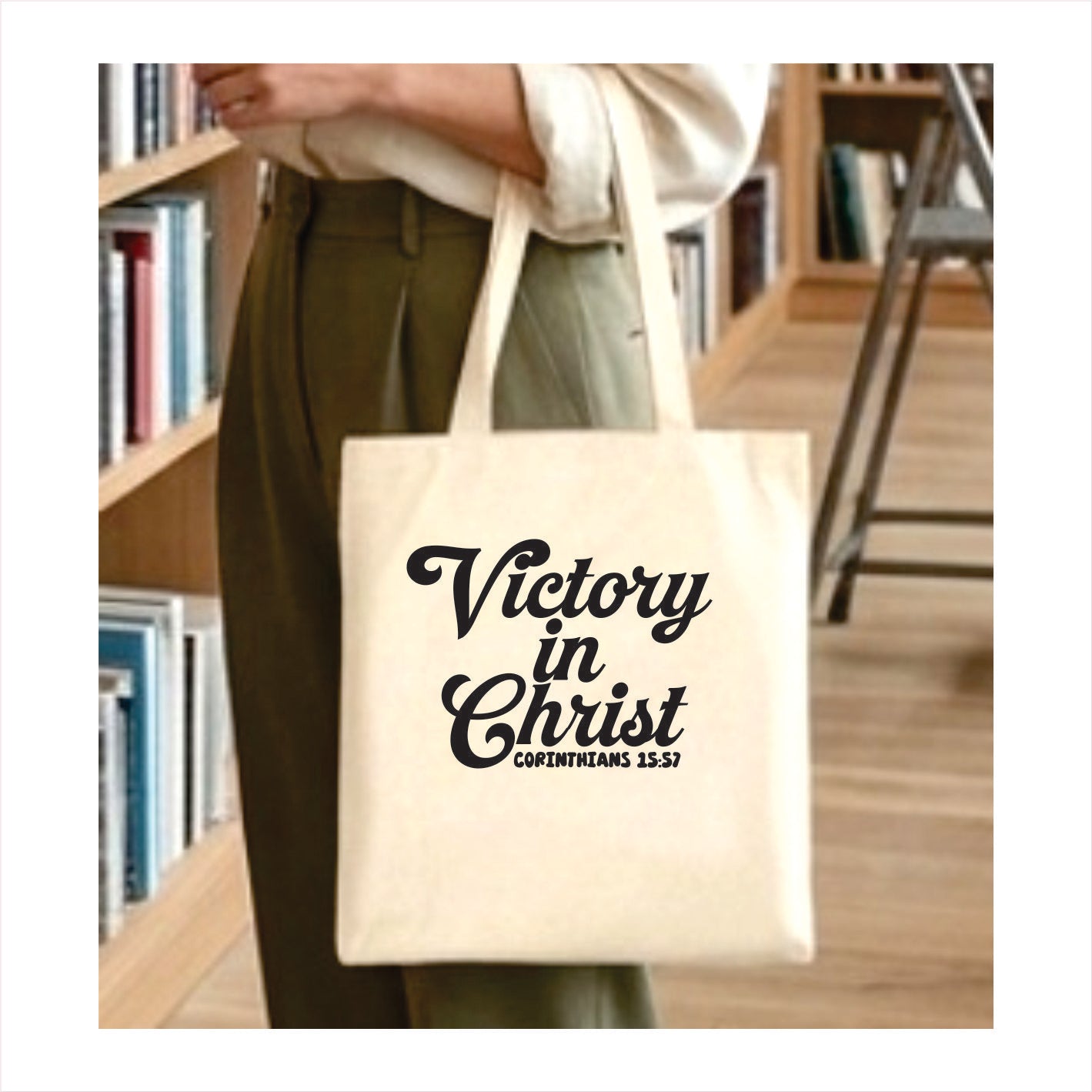 Person holding a tote bag with 'Victory in Christ' text in a library setting