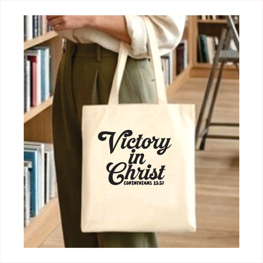 Person holding a tote bag with 'Victory in Christ' text in a library setting